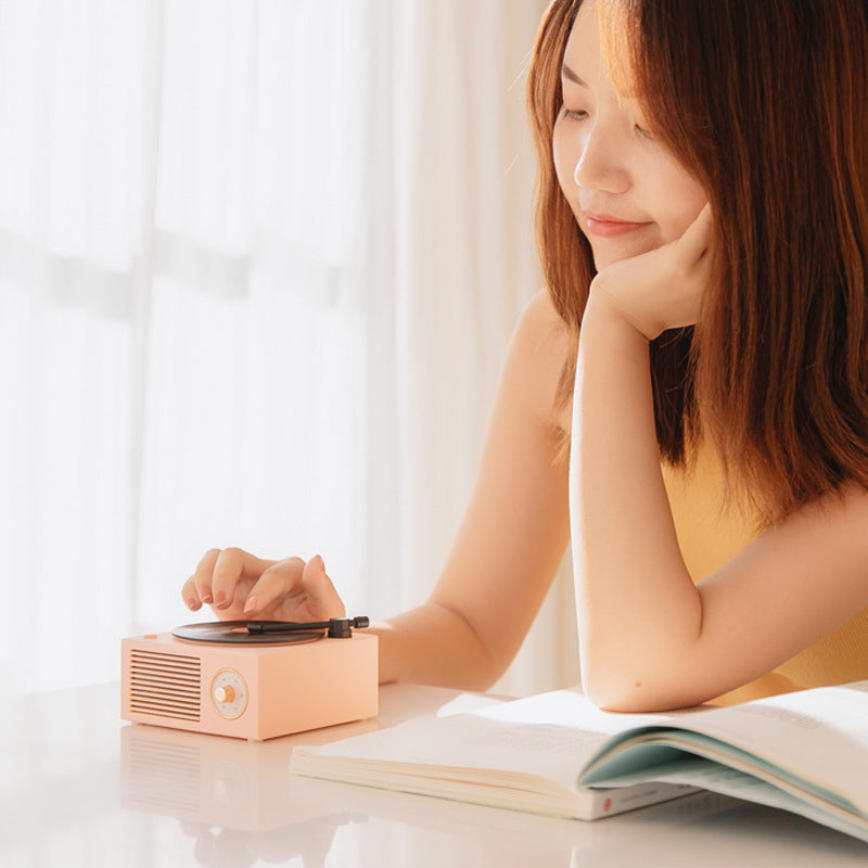 Woman enjoying music with a Wireless Bluetooth speaker while reading.