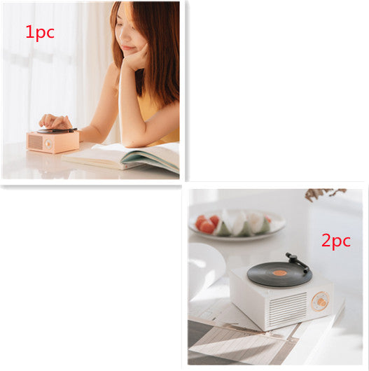 Wireless Bluetooth speaker on a table with a young woman enjoying music while reading.